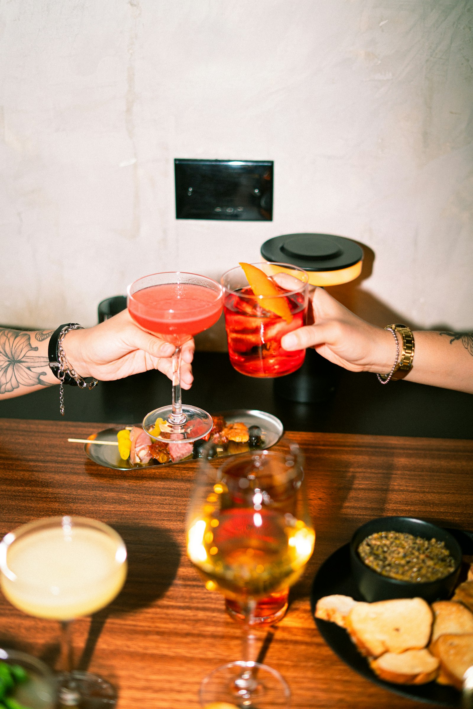 Friends raising cocktails over a table of food